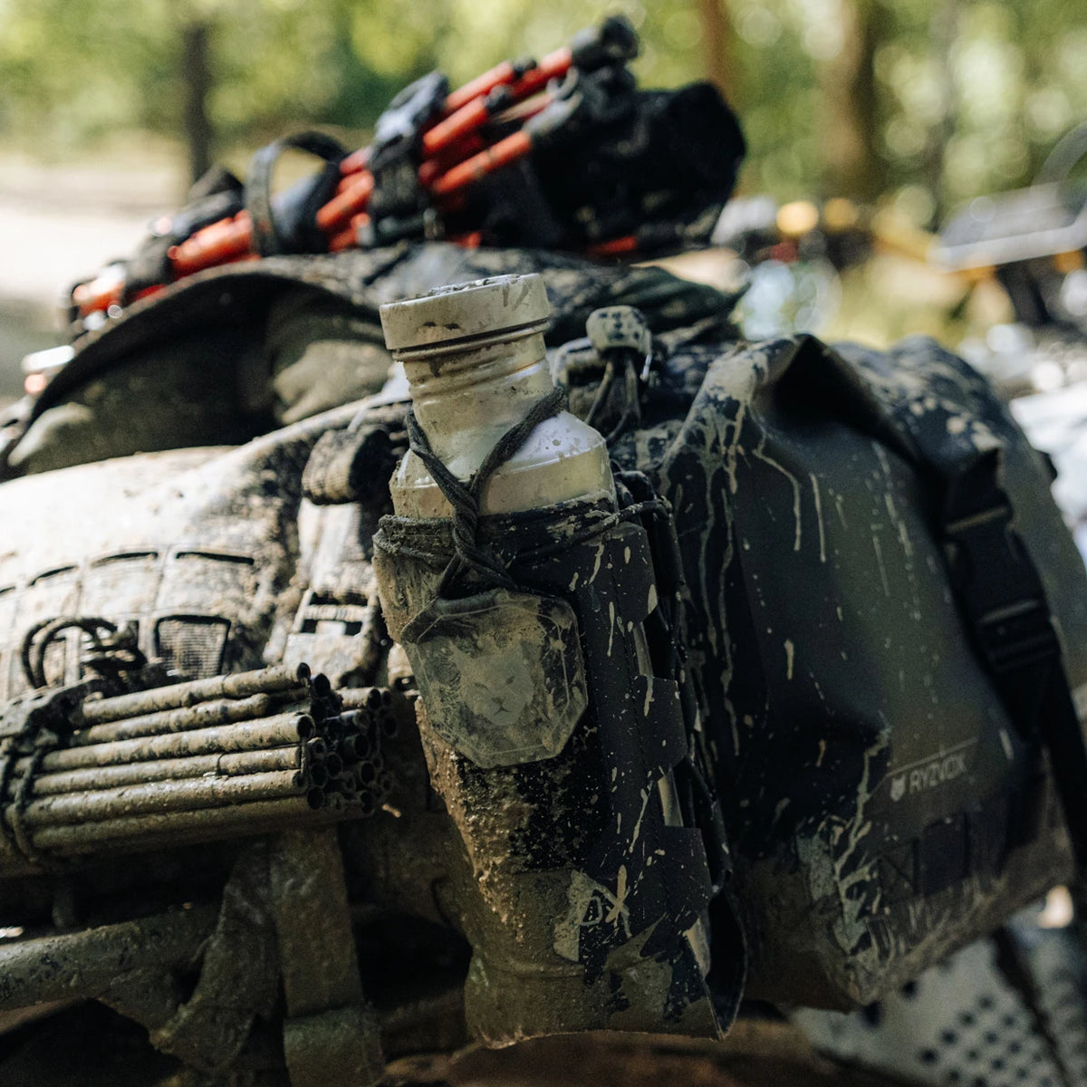 RYZVOX Bottle Holder mounted on a mud-covered motorcycle luggage setup on the trail