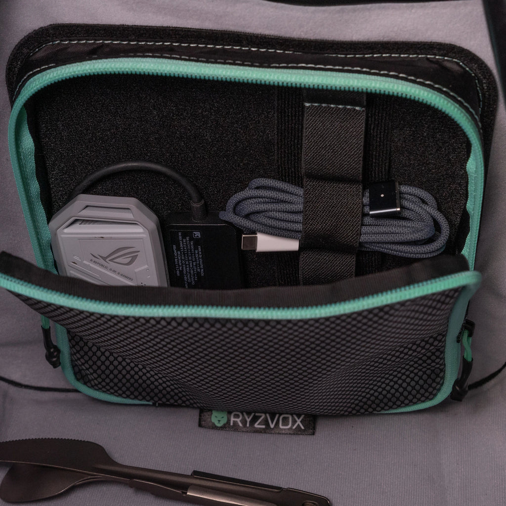 Mesh pouch open inside a RYZVOX bag, holding a laptop charger and cables