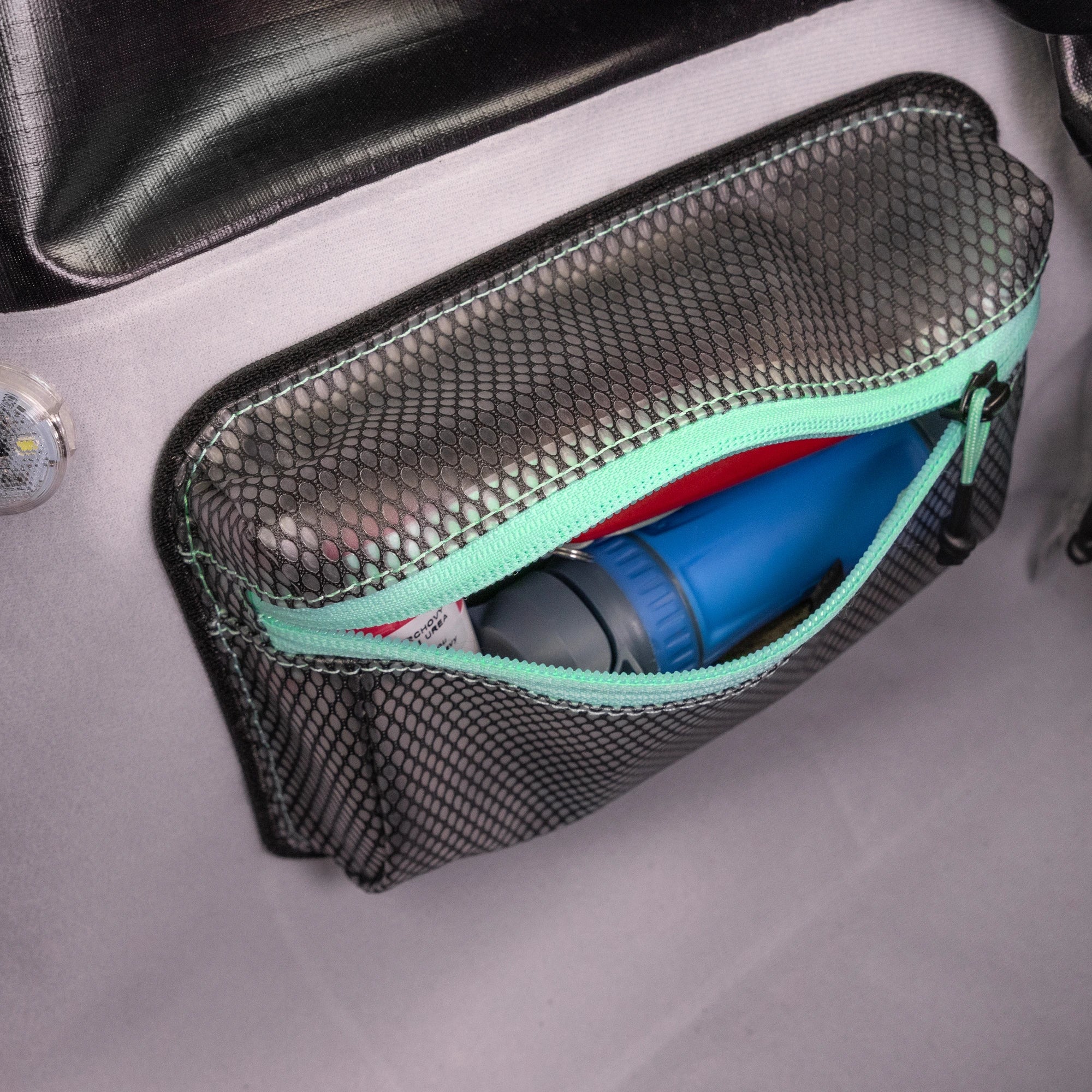 Mesh pouch open inside a RYZVOX bag, holding a water bottle and small gear