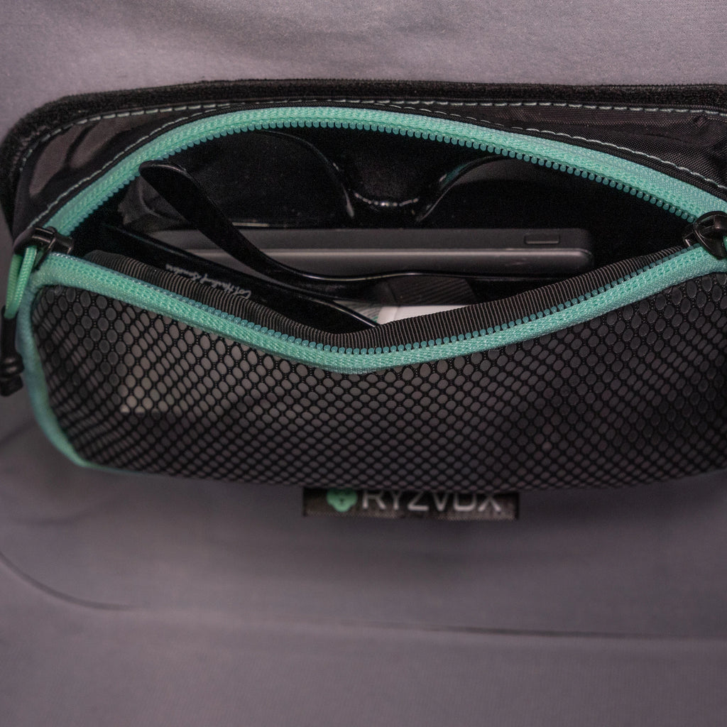 Mesh pouch open inside a RYZVOX bag, holding a phone and sunglasses