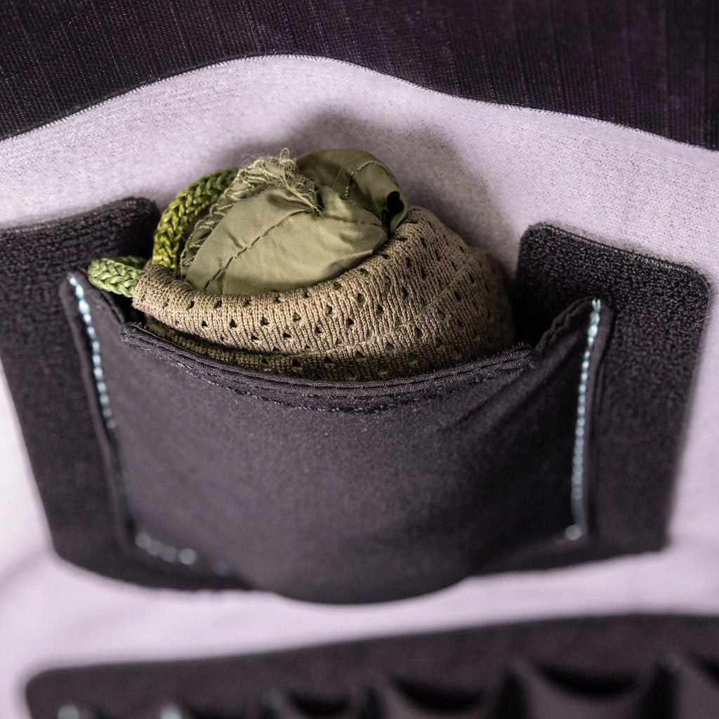 Stretch pocket mounted inside a RYZVOX bag, holding a folded cap