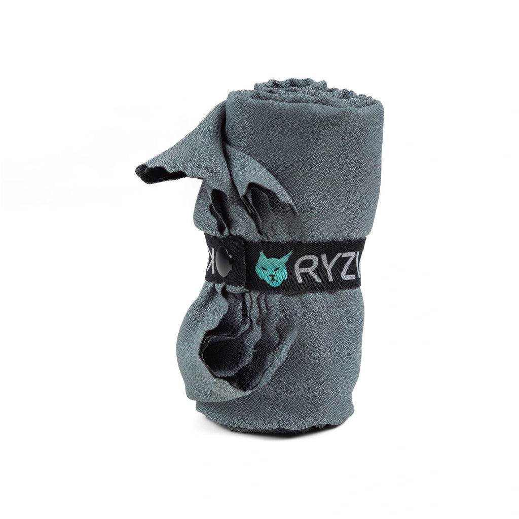 RYZVOX Ultralight Towel L standing rolled with the RYZVOX logo on the retaining strap